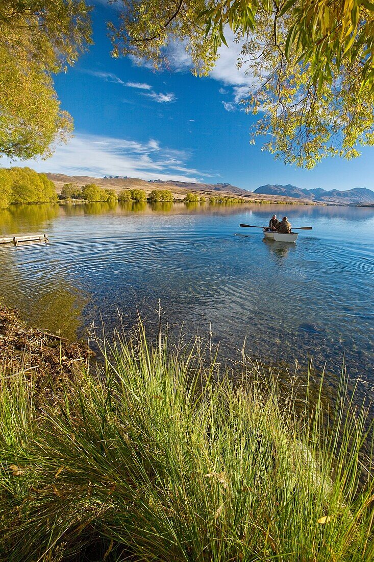 Trout fishermen set out for a morning's fishing in rowing boat no engines allowed on lake Lake Alexandrina Wildlife Refuge, Mackenzie country, Canterbury