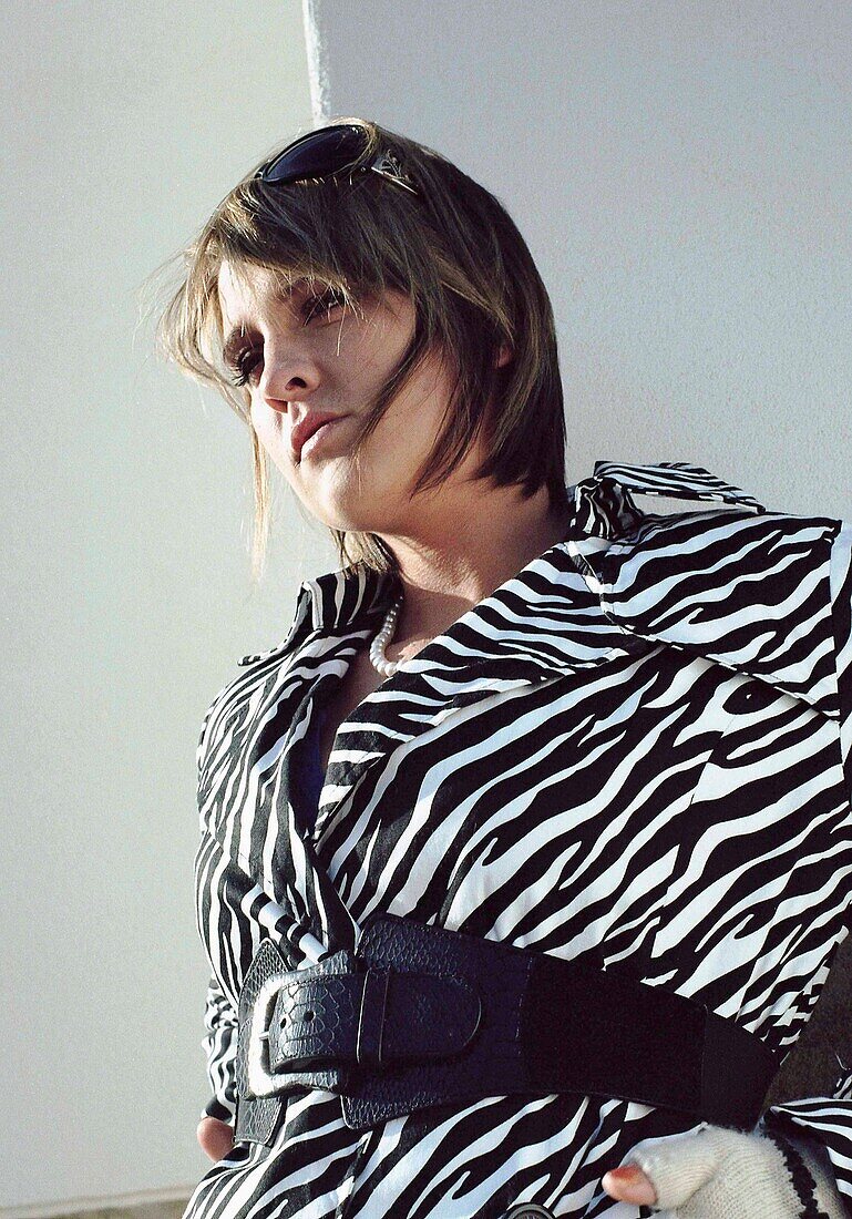 Woman in zebra coat, against white wall