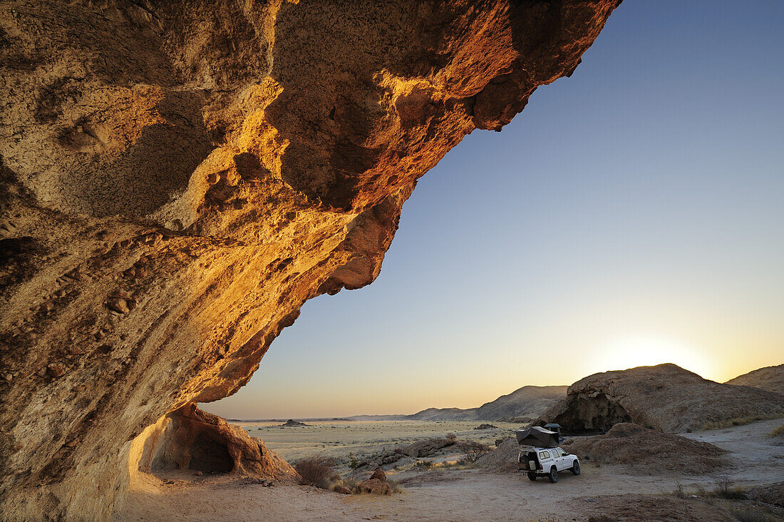 Auto mit Dachzelt steht unter Felsüberhang, Namib Naukluft National Park, Namibwüste, Namib, Namibia