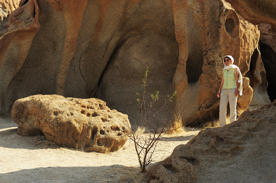 Frau geht durch Felsenlandschaft mit bizarrer Winderosion, Namibwüste, Namib, Namibia