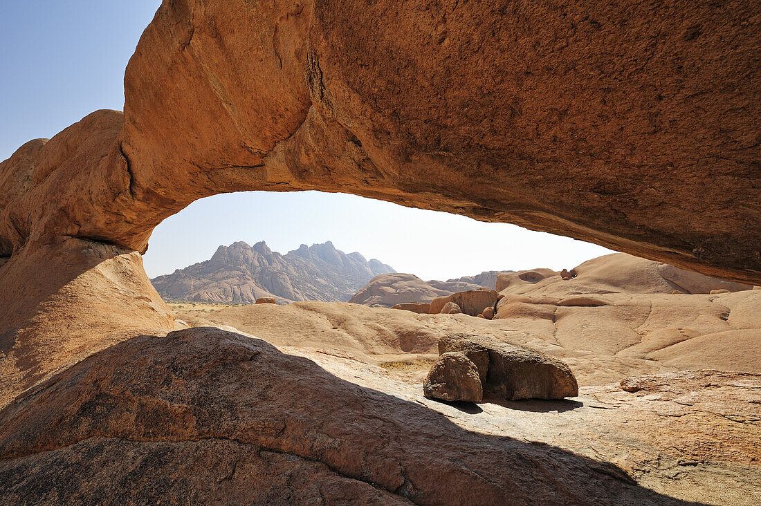 Red granite rock arch with Pontok in background, Spitzkoppe, Namibia