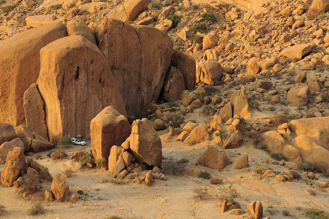 Auto mit Dachzelt steht zwischen roten Felsblöcken, Große Spitzkoppe, Namibia