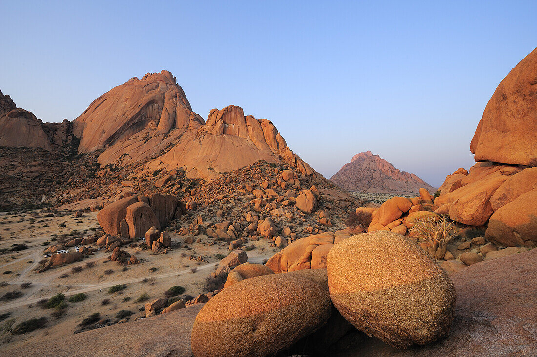 Rote Granitfelskugel auf Felsplatte vor Große Spitzkoppe und Pontok, Große Spitzkoppe, Namibia