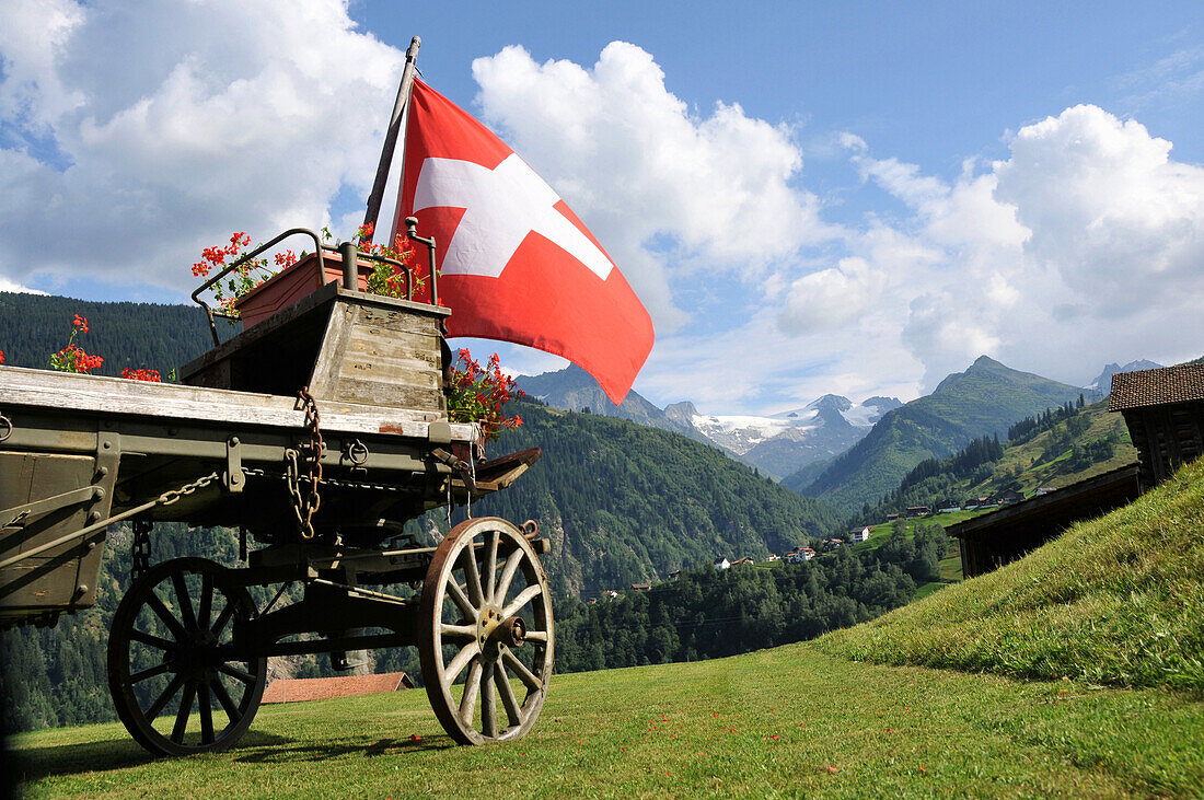 Schweizer Flagge an einem alten Fuhrwerk, bei Disentis, Graubünden, Schweiz