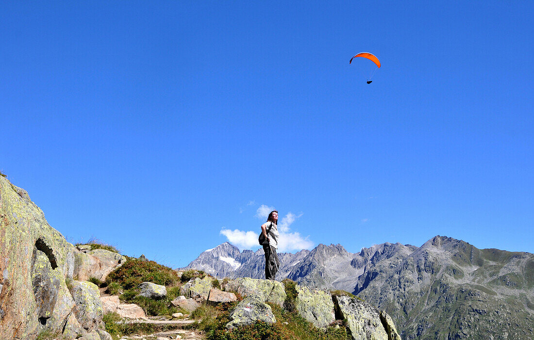 Woman watching paraglider, Fiescheralp, Valais, Switzerland