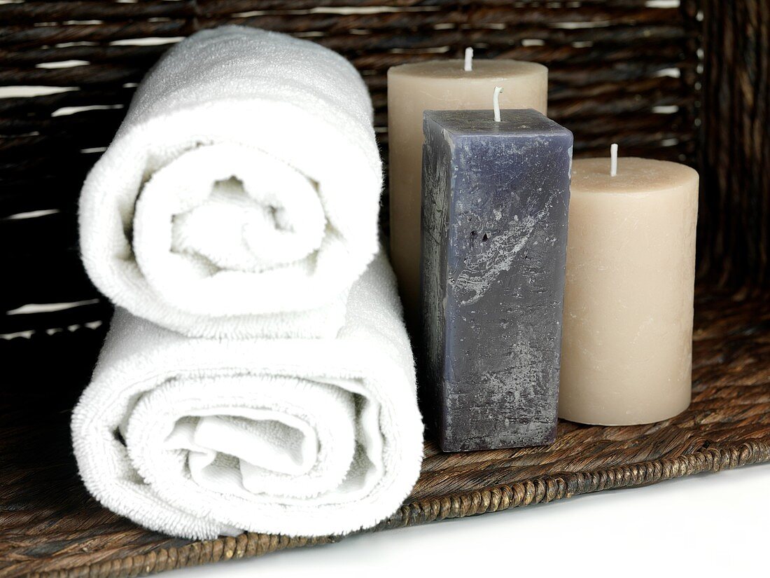 Scented candles in a basket with bath towels