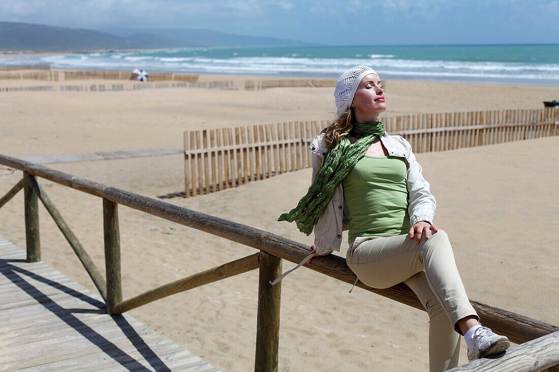 Woman in Barbate beach and wooden barriers supposed to hinder the sand from invading the promenade. Barbate. Cádiz province. Andalusia. Spain