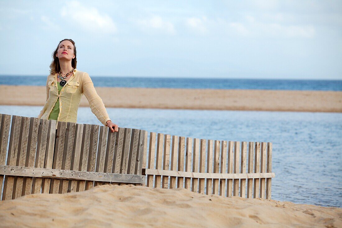 Woman close barriers against moving dunes in Valdevaqueros beach, Tarifa. Cádiz province, Andalusia. Spain