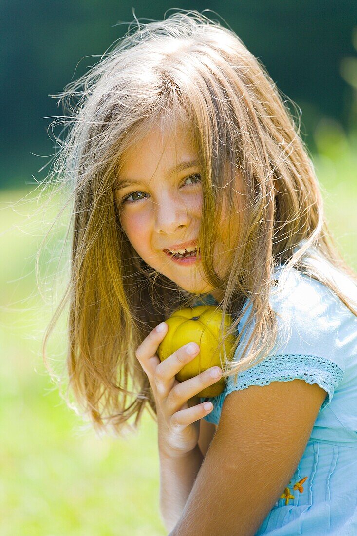 Six year old girl is holding a pear