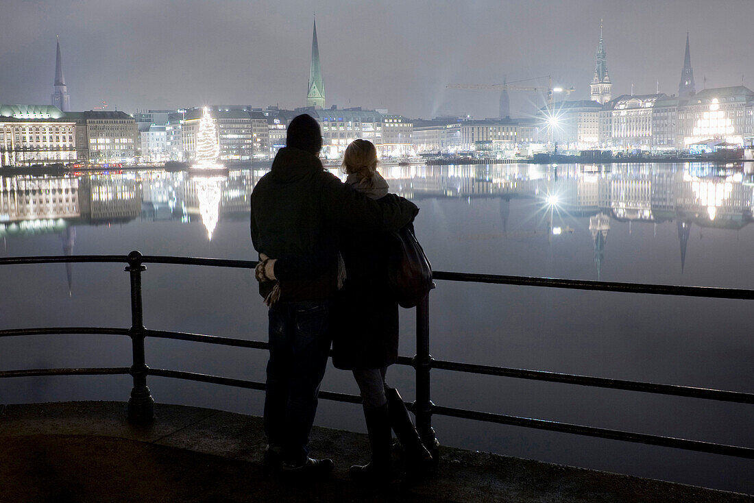 Paar blickt über Binnenalster auf weihnachtlich beleuchtete Stadt, Hamburg, Deutschland