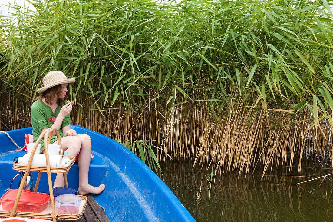 Mädchen mit Strohhut beim Picknick in einem Boot, Teupitzer See, Brandenburg, Deutschland