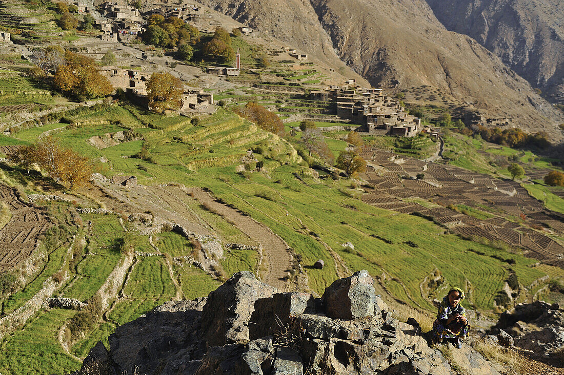 Girl and village amidst fields  in Ourika valley, trekking in the High Atlas from Imlil, Toubkal Area, Morocco