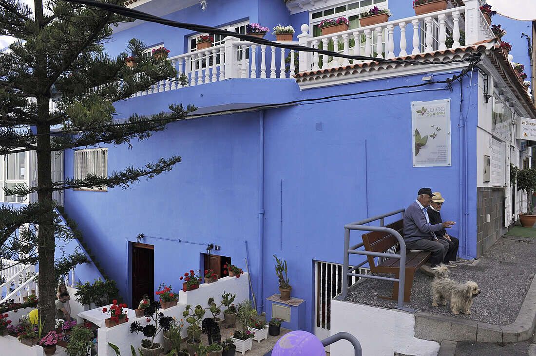 Two elderly men on a bench in front of a blue house, El Sauzal, Casa del Vino,  Tenerife, Canary Islands, Spain