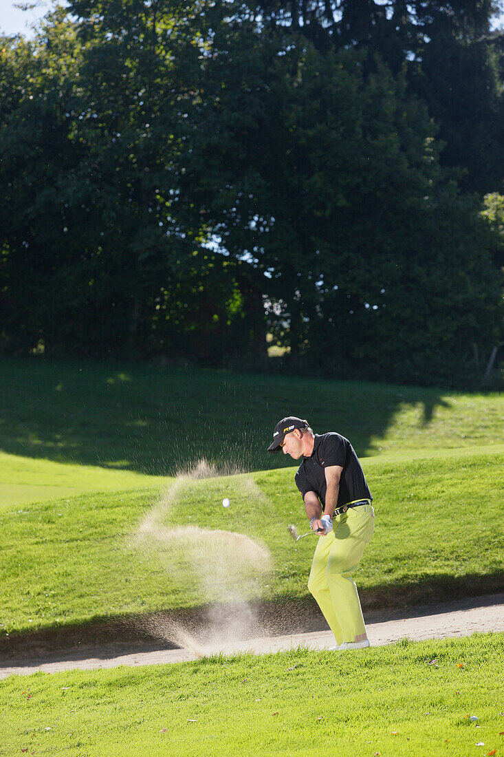 Golfspieler beim Abschlag aus Bunker, Prien am Chiemsee, Bayern, Deutschland