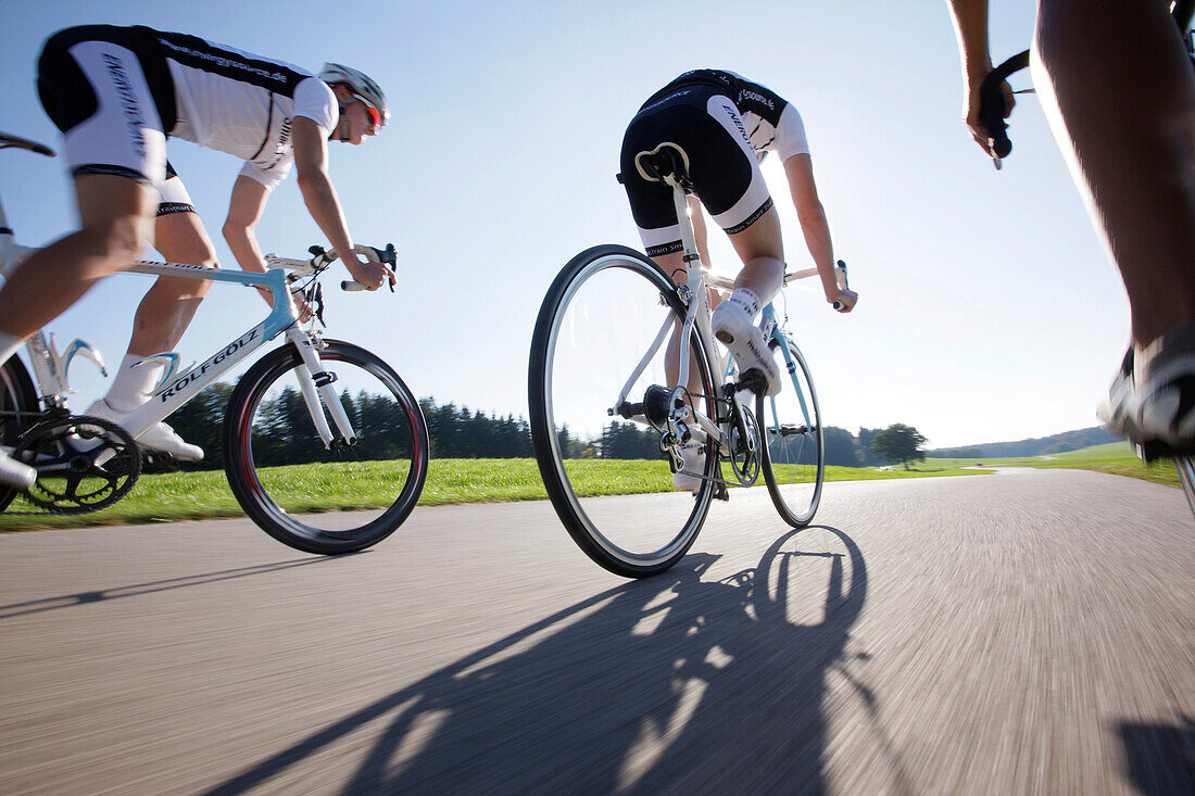Three racing cyclists on road near Munsing, Upper Bavaria, Germany