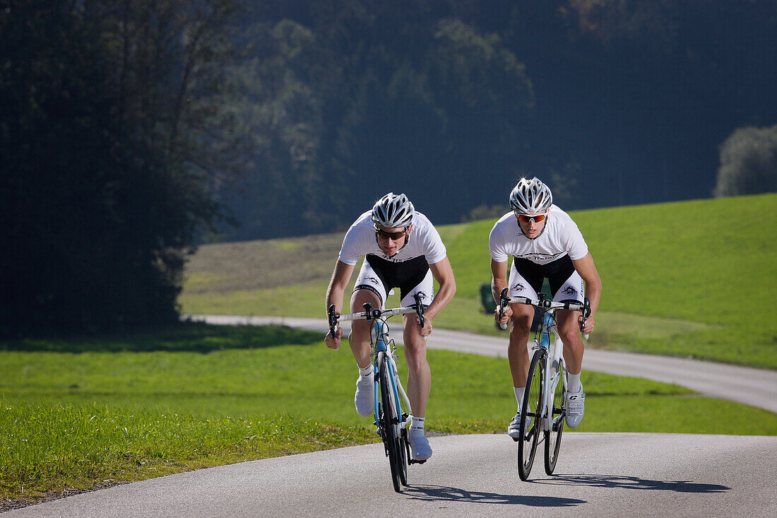 Zwei Radrennfahrer auf einer Landstraße bei Münsing, Oberbayern, Deutschland