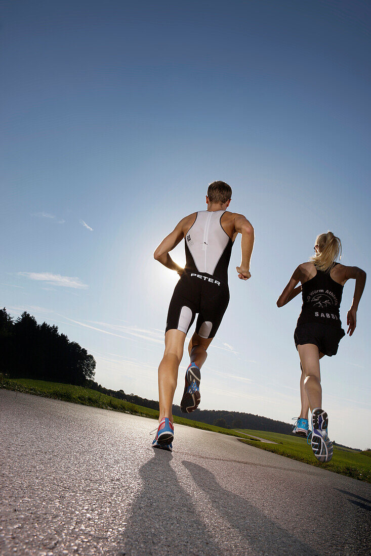 Two runners on road near Munsing, Upper Bavaria, Germany