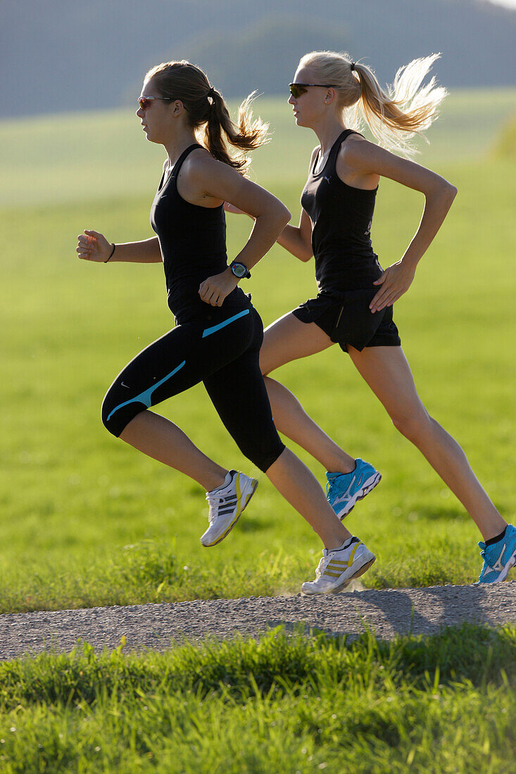 Two female runners on path near Munsing, Upper Bavaria, Germany