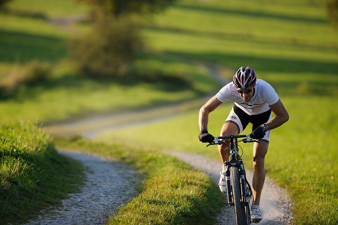 Mountainbiker auf einem Feldweg bei Münsing, Oberbayern, Deutschland