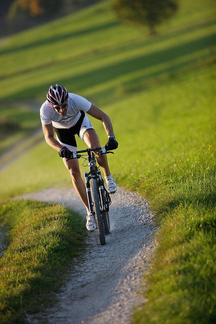 Man mountain biking on dirt track near Munsing, Upper bavaria, Germany