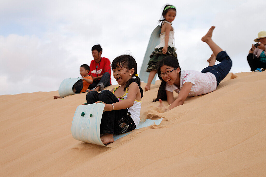 Kinder rutschen Sanddünen hinunter, Weiße Dünen, Mui Ne, Binh Thuan, Vietnam