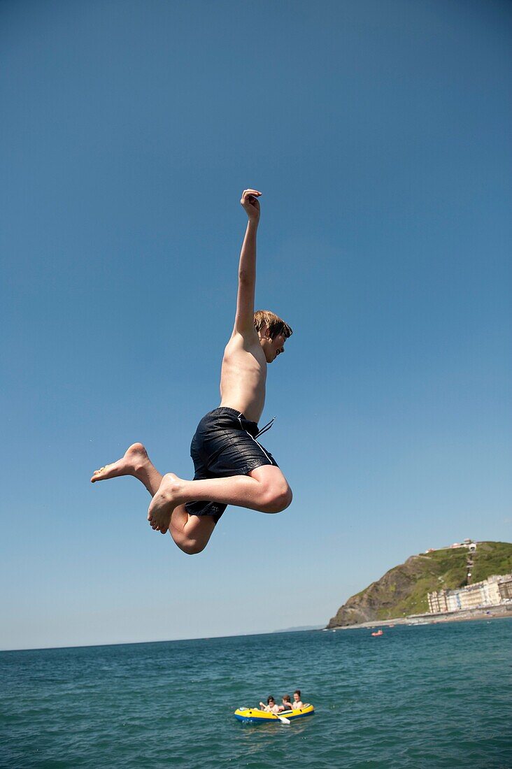 A man jumping into the sea, Aberystwyth seaside resort, wales UK, summer afternoon