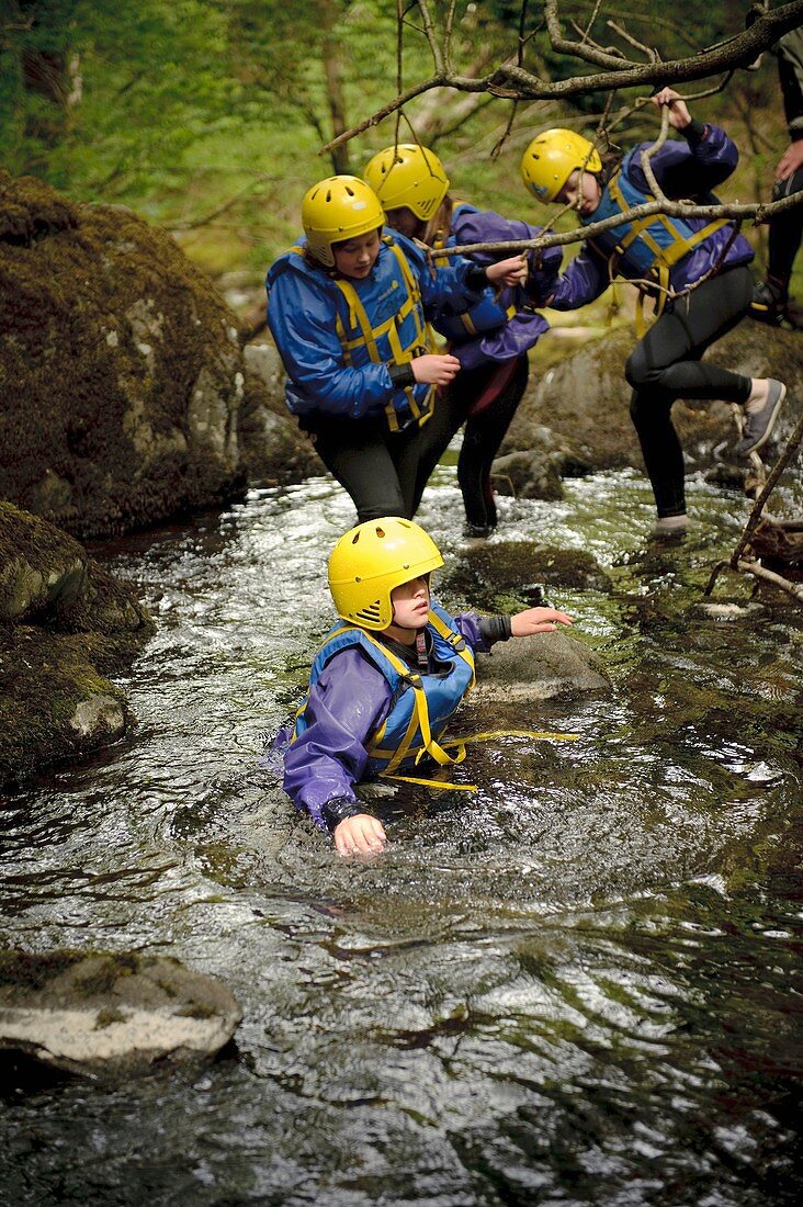 Young children walking in the River Arran near Dolgellau as part of a course organised by the Canolfan Yr Urdd outward bound adventure centre, Glanllyn, Bala, North Wales UK