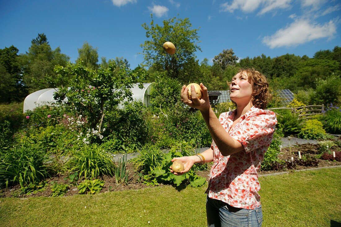 A woman juggling with three potatoes at The Centre for Alternative Technology, Machynlleth, Powys Wales UK