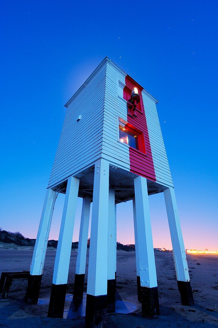 The wooden lighthouse at Burnham-on-Sea at dusk, Somerset, England, United Kingdom The glow of the moon in the sky behind the lighthouse can be seen over the roof Short star trails are visible in the sky