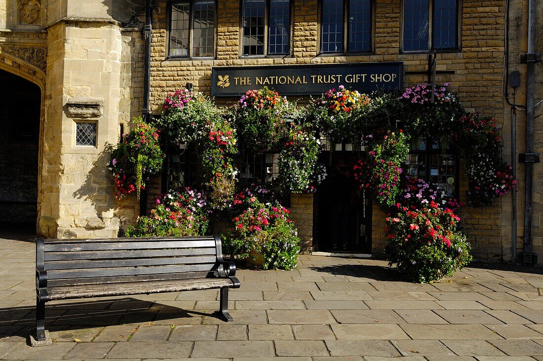 A floral display outside the National Trust gift shop by Penniless Porch in the Market Place, Wells, Somerset, England, United Kingdom