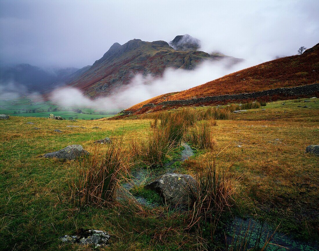 Langdale Pikes surrounded by mist viewed from Wrynose Fell near Chapel Stile in the Lake District National Park, Cumbria England, United Kingdom