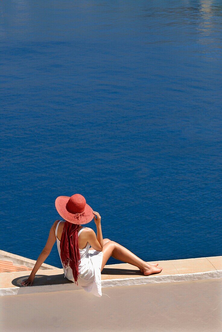 Woman sitting in front of a sweeping view of the sea in the island of Symi Greece