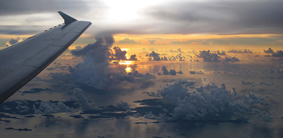 Blick aus dem Flugzeug während eines Fluges auf eine Inselgruppe unter den Wolken