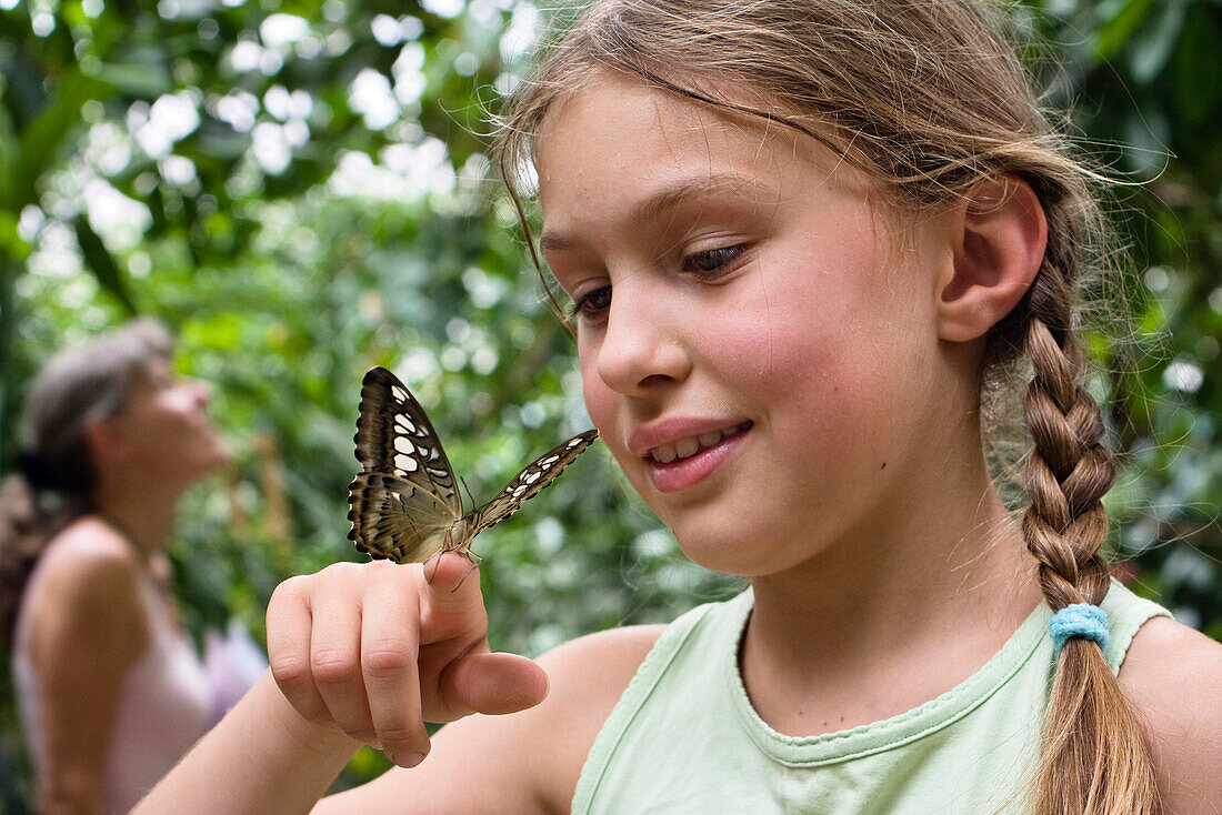 9-Jähriges Mädchen in Schmetterlingspark mit tropischem Schmetterling auf der Hand, Deutschland, Europa