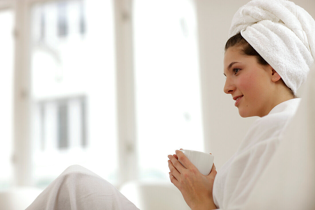 Young woman wearing bathrobe and towel chilling, Munich, Bavaria, Germany