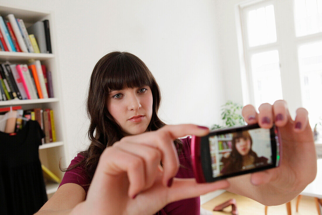 Young woman taking a photo with a mobile phone, Munich, Bavaria, Germany