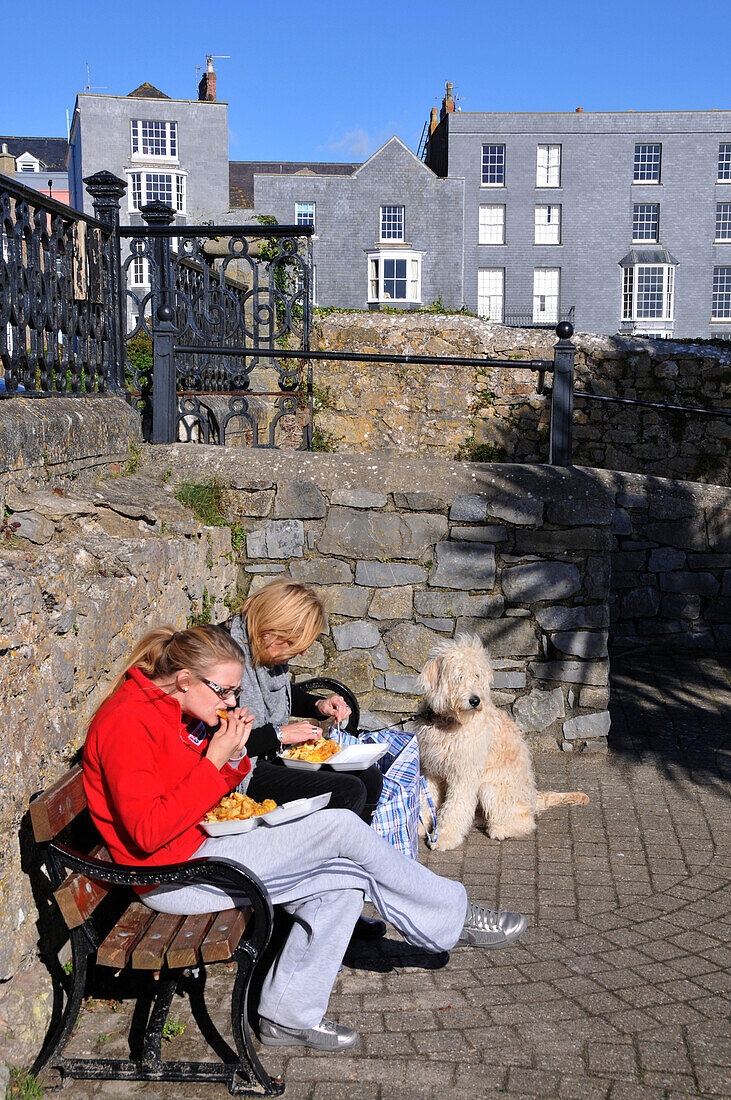 Zwei Frauen essen Fish and Chips, Meerpromenade, Tenby, Pembrokeshire, Süd-Wales, Wales, Großbritannien