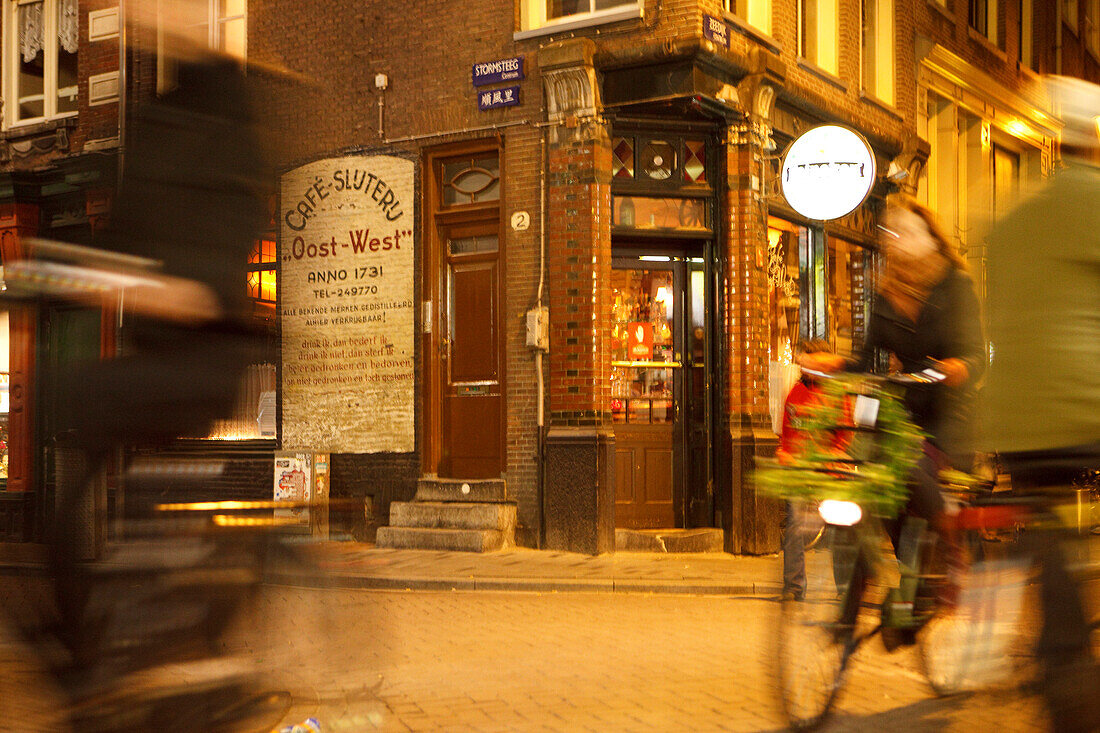Nächtliche Straßenszene mit Radfahrer in der Altstadt von Amsterdam, Niederlande