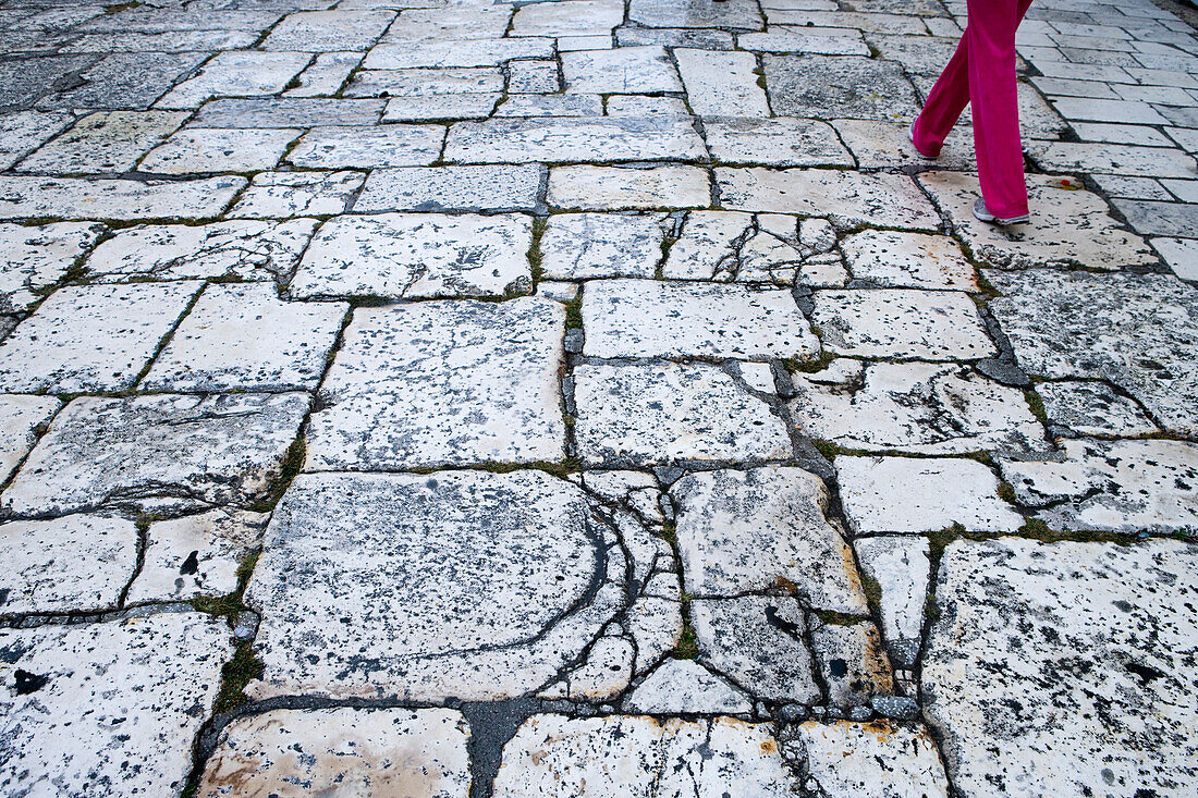 Frau mit roter Hose läuft auf Straße mit großen Pflastersteinen, Split, Dalmatien, Kroatien, Europa