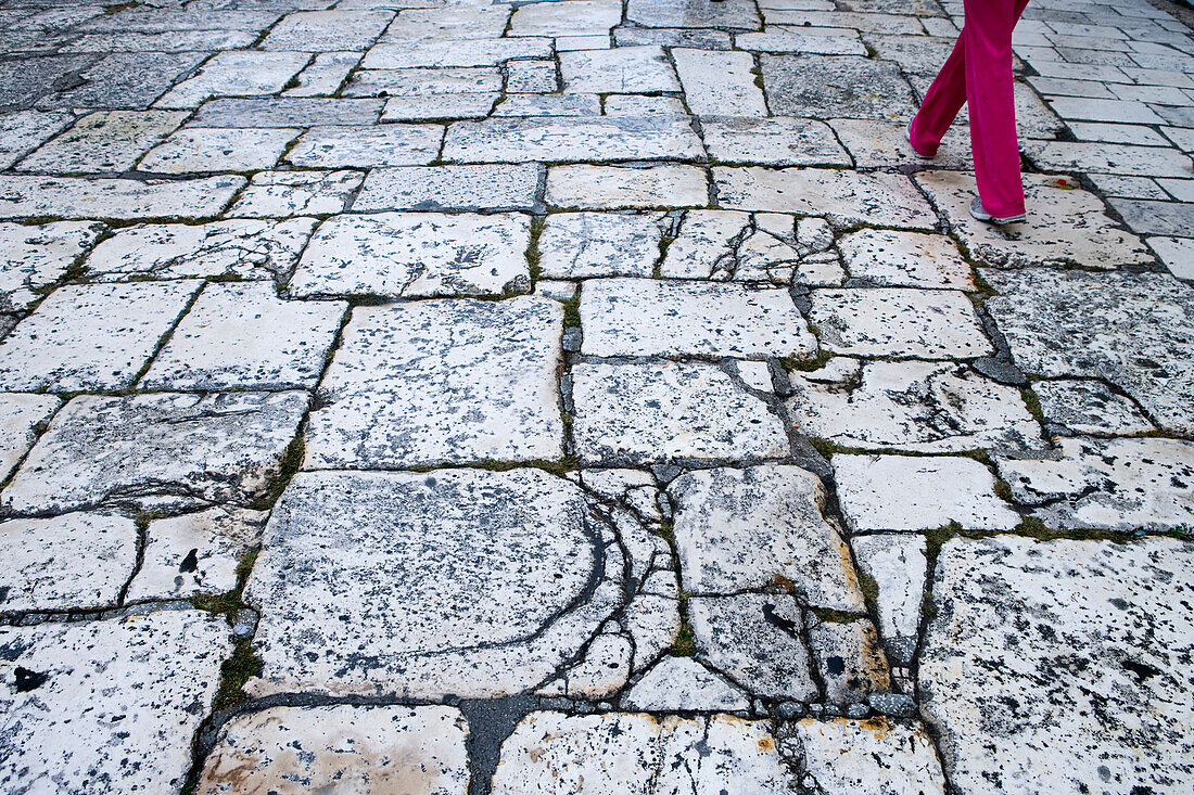 Women wearing red trousers walking down a large stone street, Split, Croatia, Europe