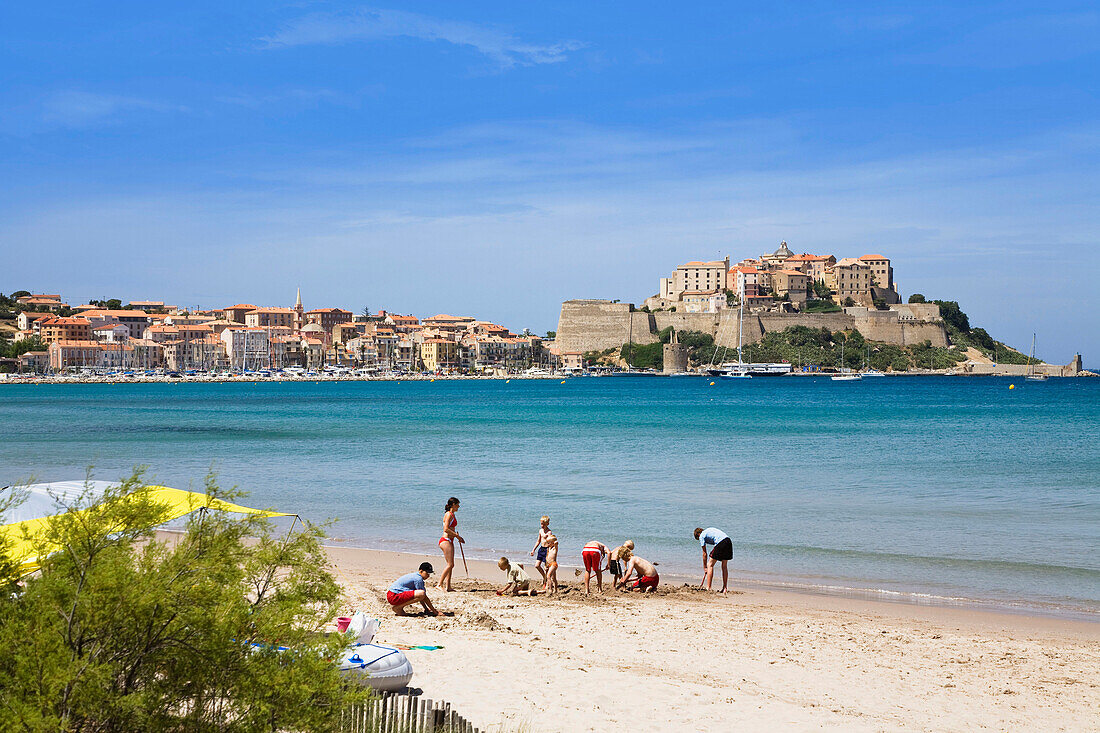 Kinder spielen am Strand, Zitadelle im Hintergrund, Calvi, Korsika, Frankreich
