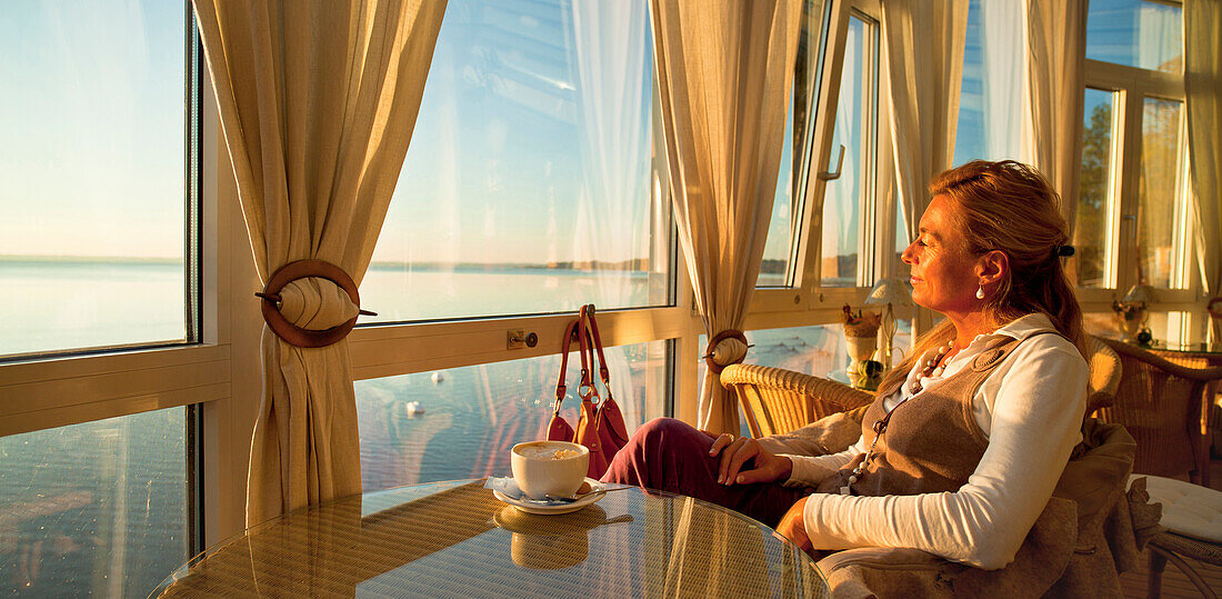 Eine Frau im Café mit Blick auf den Chiemsee, Chieming, Chiemsee, Chiemgau, Oberbayern, Bayern, Deutschland