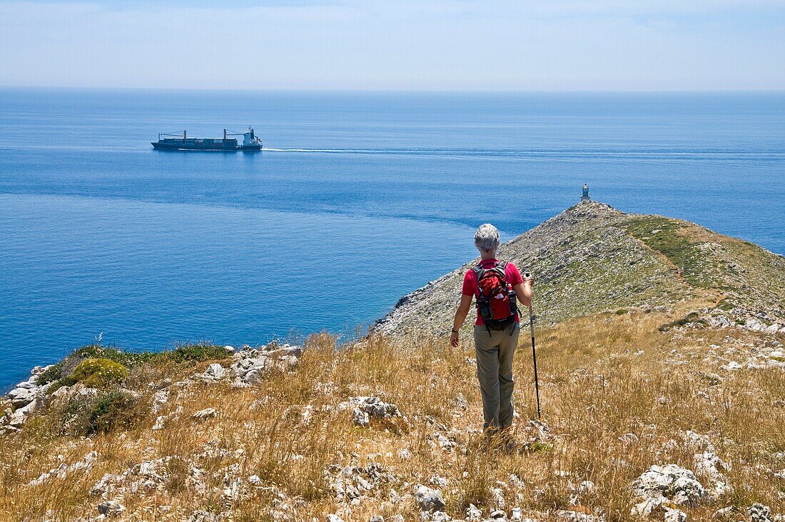 A lone walker on a ridge descending to the Lighthouse at the tip of Cape Tenaro in the deep Mani, Peloponnese, Greece
