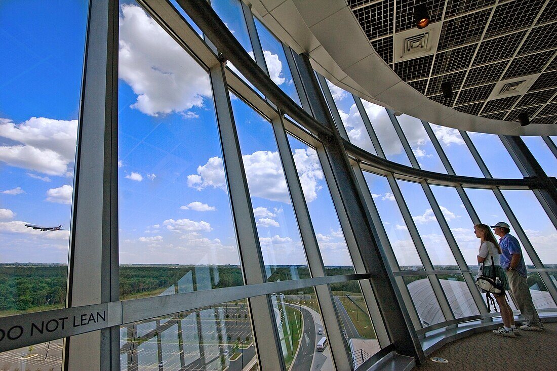 Two people watch a jumbo jet land at Dulles international airport from the Smithsonian observation tower in Dulles, Virginia