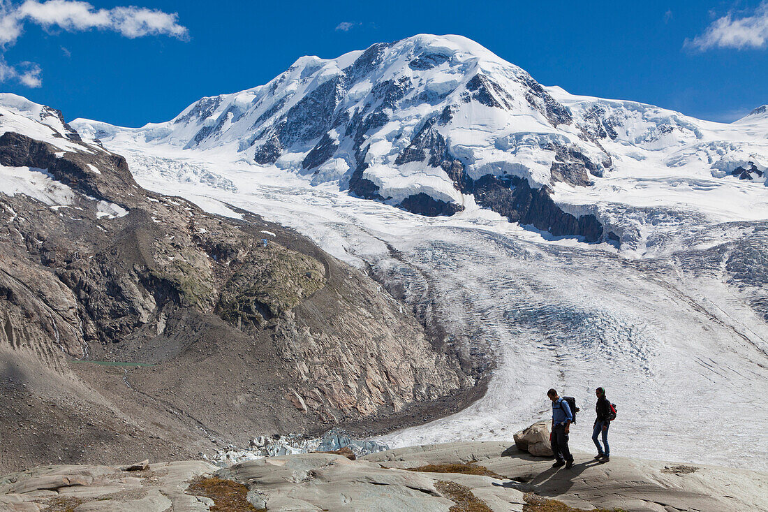Zwei Wanderer am Grenzgletscher, Weg zur Monte-Rosa-Hütte, Liskamm im Hintergrund, Zermatt, Kanton Wallis, Schweiz, Klimahörpfad von myclimate
