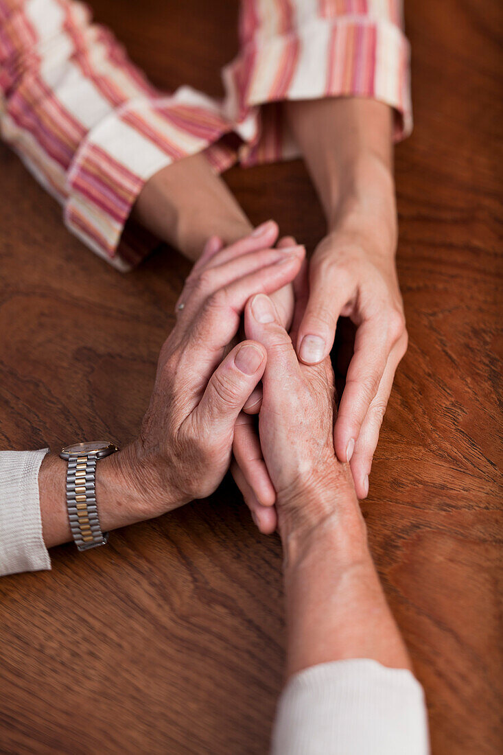 Eine alte und eine ältere Frau halten sich an den Händen
