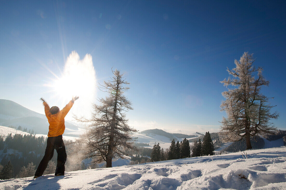 Mann wirft Schnee hoch, Steiermark, Österreich