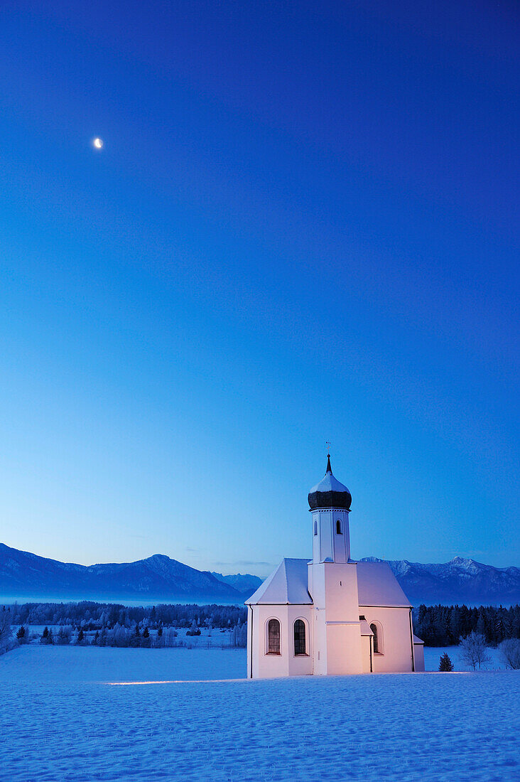 Verschneite Kirche vor Alpenkette am Abend, Penzberg, Werdenfelser Land, Oberbayern, Bayern, Deutschland, Europa