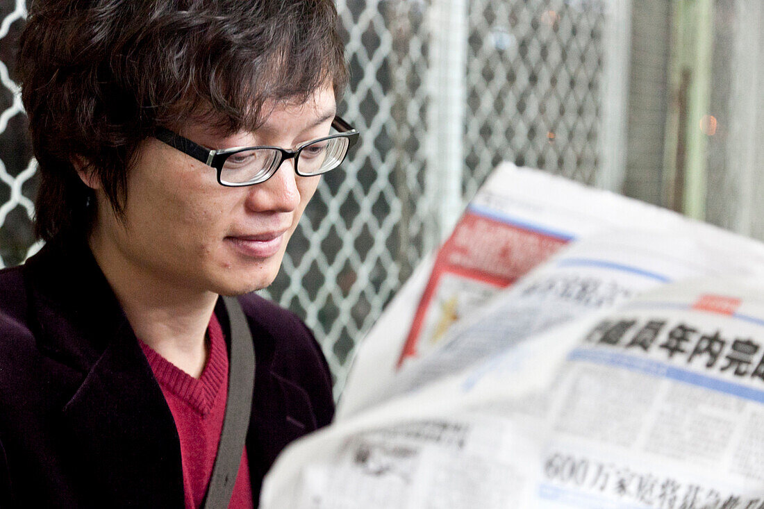 Junger Chinese liest Zeitung, chinesische Schriftzeichen, Peking, VR China