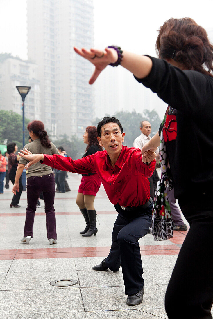 Tänzer, Paar, Mann und Frau, Tanzlehrer in rotem Hemd, Gruppe von Tänzern auf dem Platz vor dem Walmart Einkaufszentrum, viele Chinesen treffen sich zum gemeinschaftlichem Tanz, Stadtteil Shapingba von Chongqing, Hochäuser, Chongqing, VR China